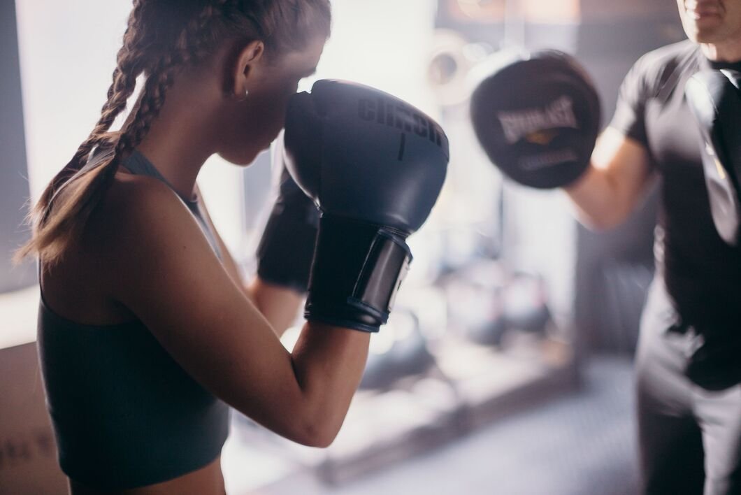 Niña en posición de guardia de boxeo con guantes de boxeo entrenando sobre un ring